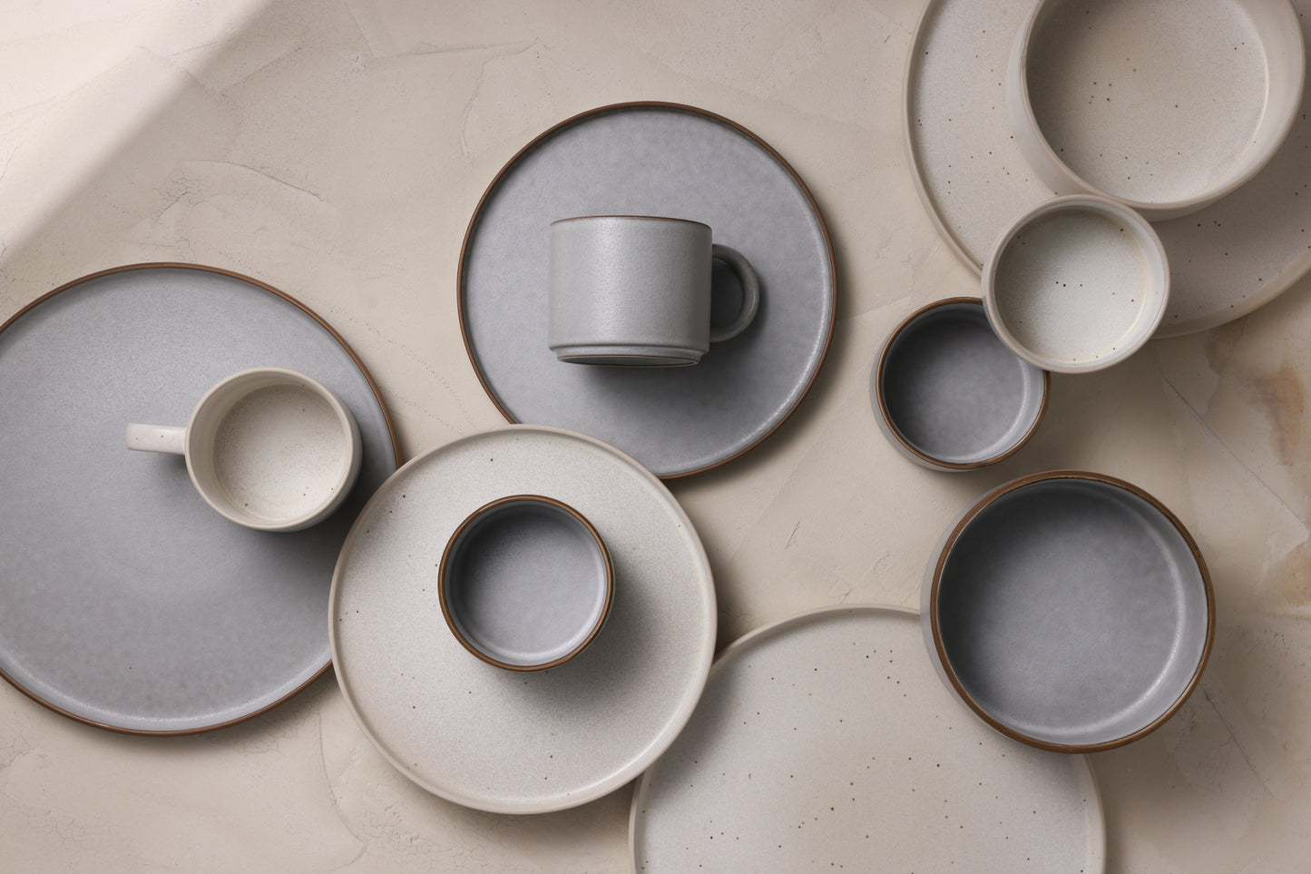 A calm arrangement of stoneware bowls, plates and mugs in gray and white