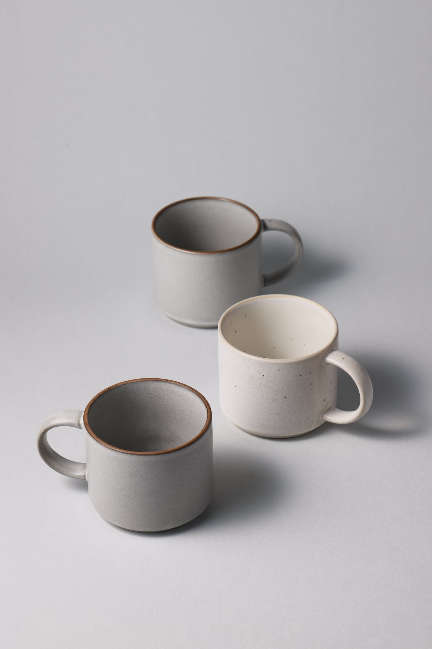 Three stoneware mugs with matte finish in soft gray and beige