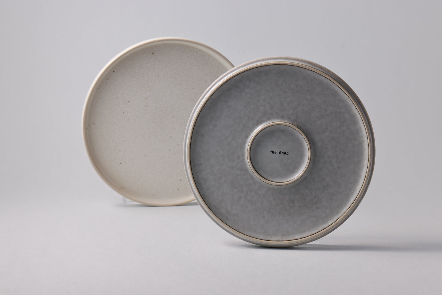 Stoneware plates with a matte finish, shown together in soft grey and white