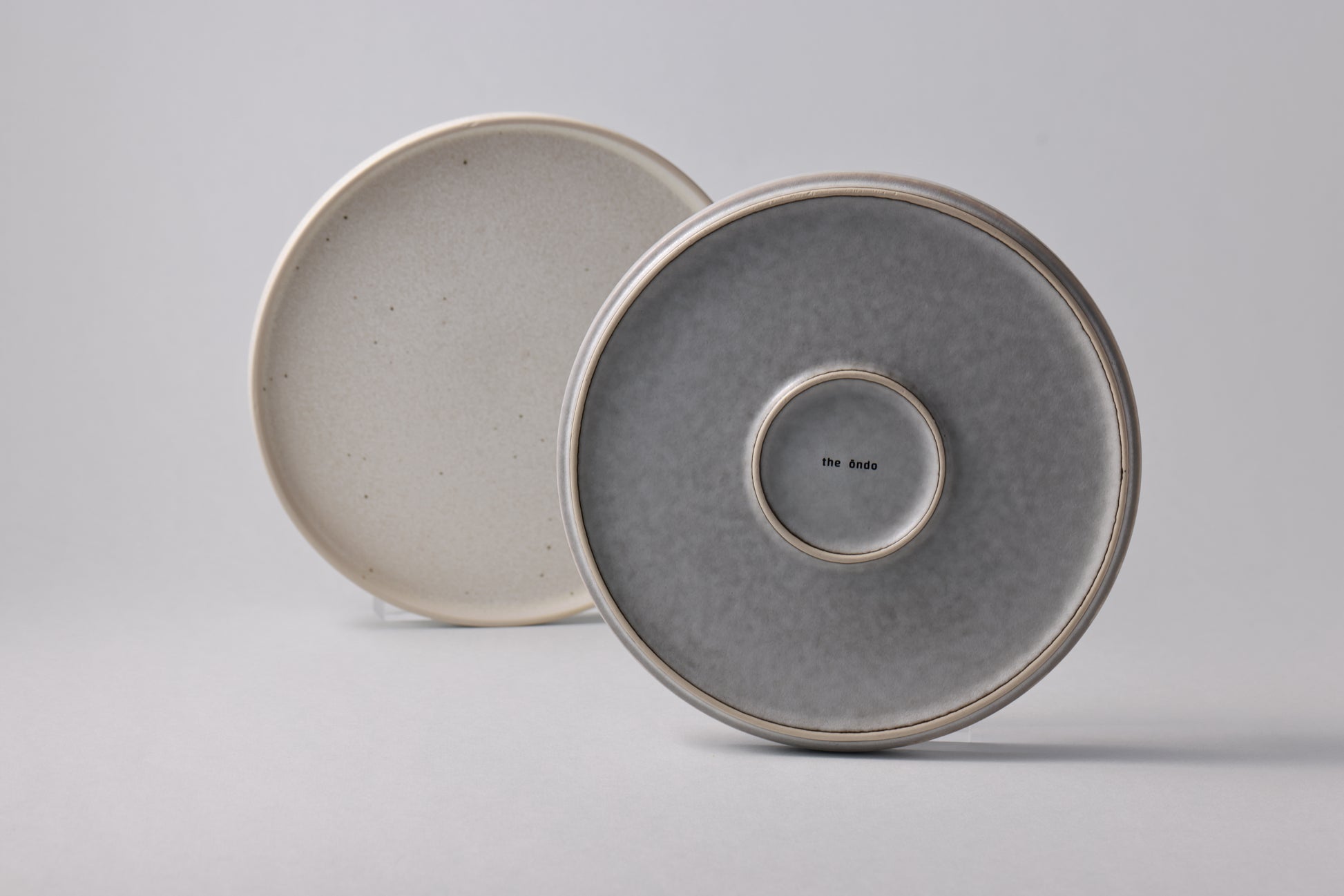 Stoneware plates with a matte finish, shown together in soft grey and white