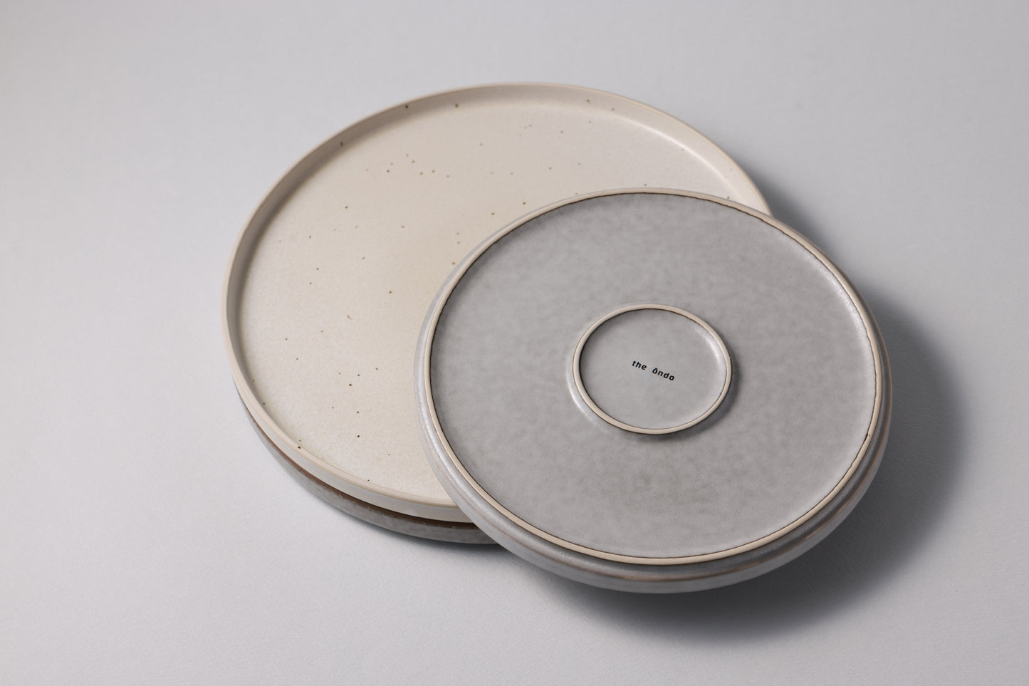 Stoneware plates in two sizes with a matte finish, shown together in soft grey and white