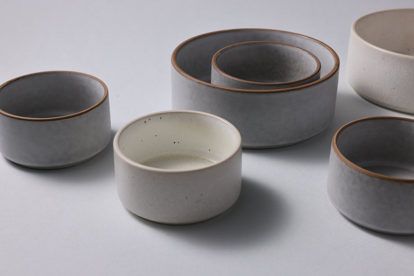Two sizes of matte stoneware bowls arranged together, highlighting scale and quiet form