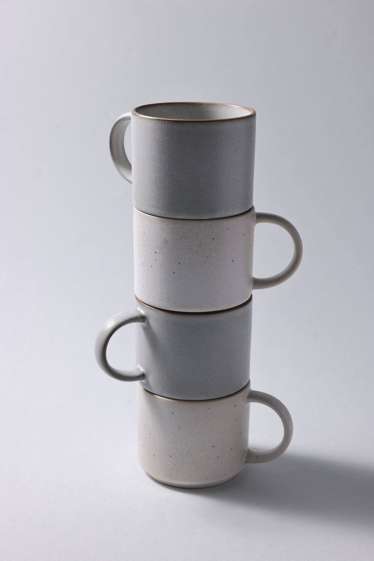 Stack of stoneware mugs with matte finish in soft gray and beige