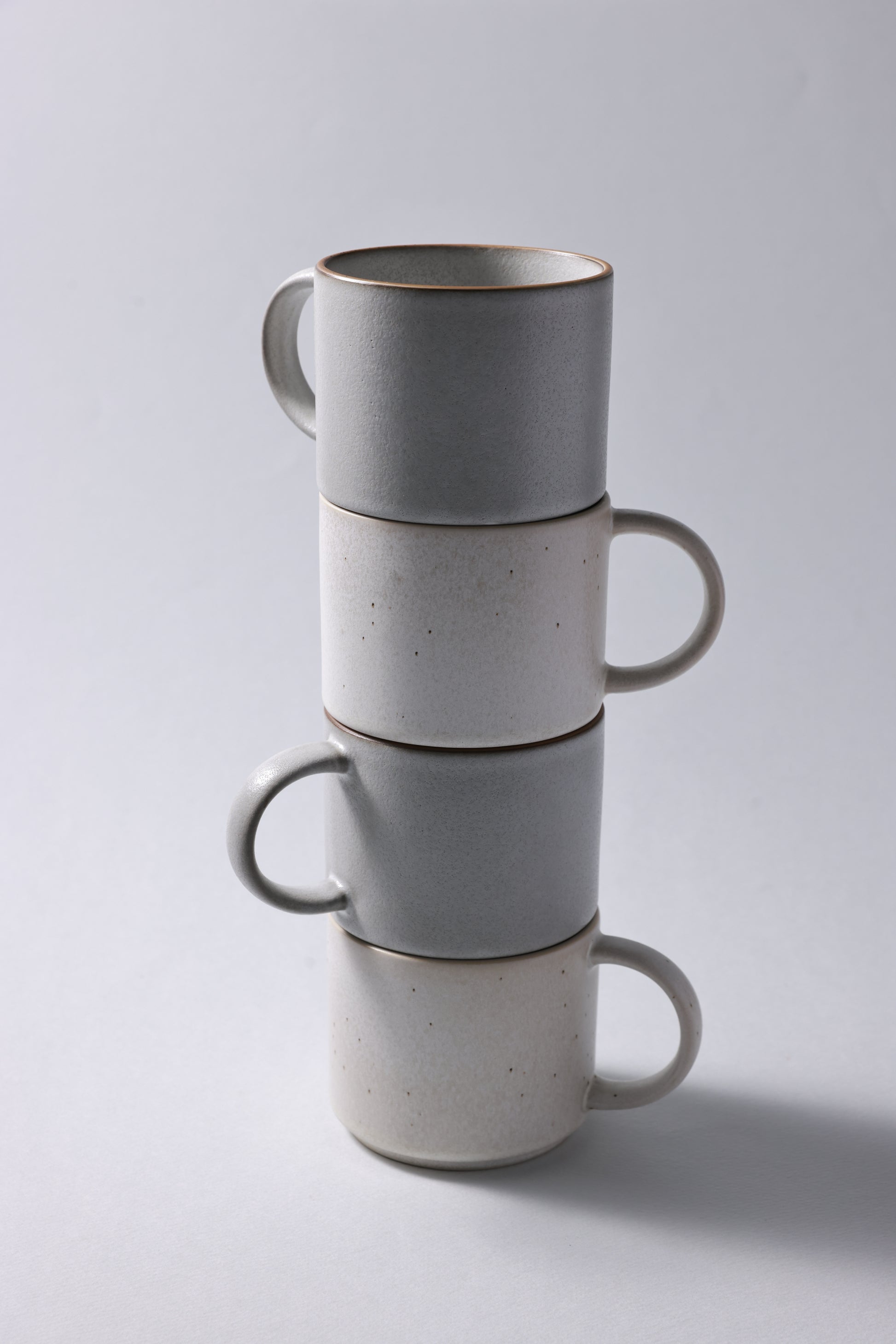 Stack of stoneware mugs with matte finish in soft gray and beige