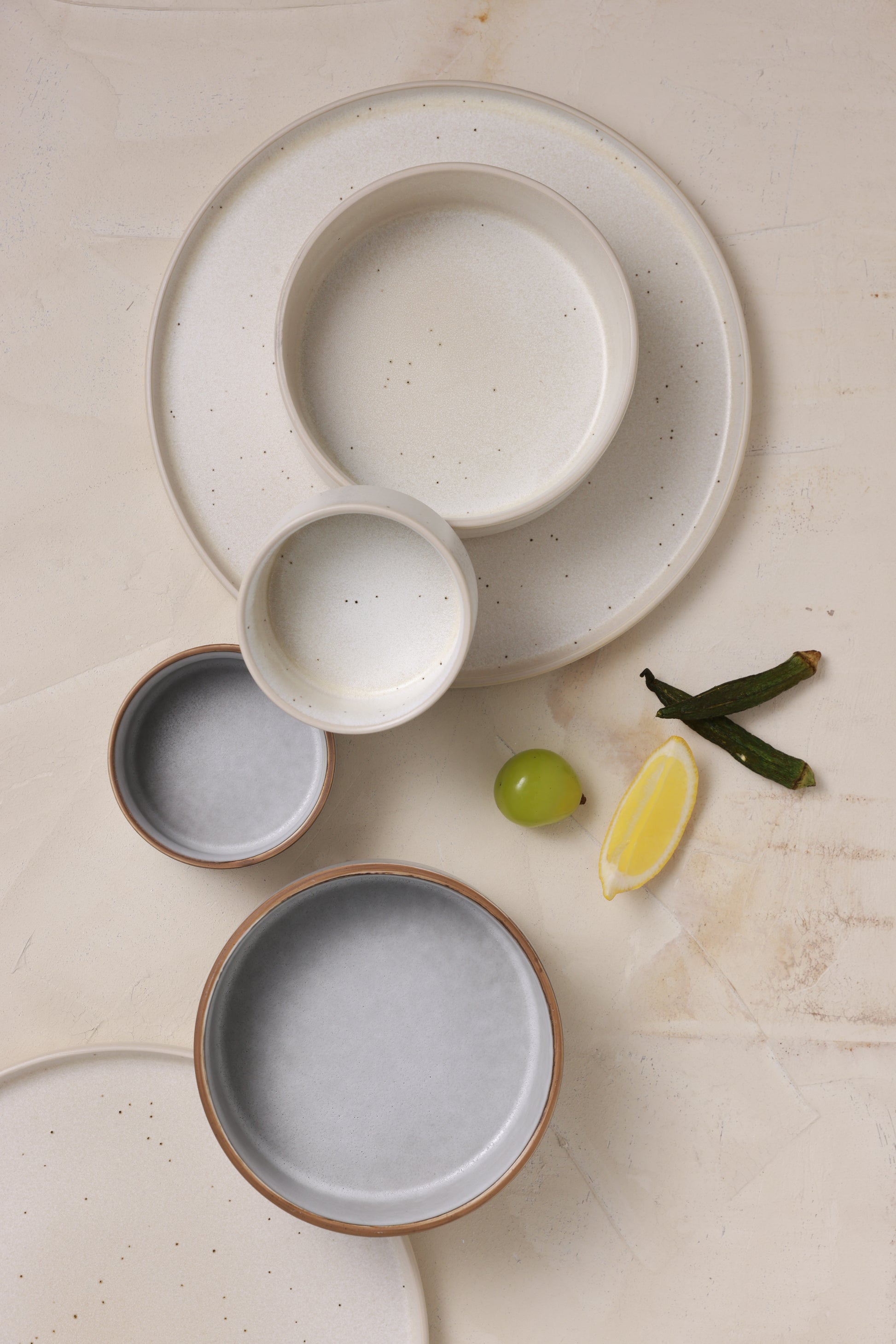 A calm table setting featuring matte stoneware bowls and plates